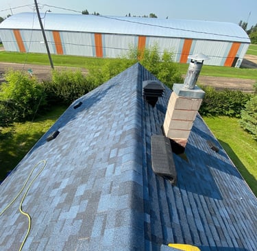 A steep residential roof in Abbotsford with new blue asphalt shingles, and roof vents installed 