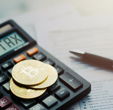 Gold Bitcoin coins on a calculator showing TAX for cryptocurrency tax filing and accounting.