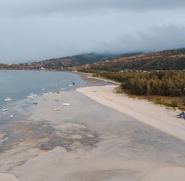 Aerial view of a peaceful beach on Rodrigues Island, with fishing boats anchored near the shore