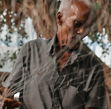 Portrait of elderly fisherman through fishing net, Mahebourg, Mauritius