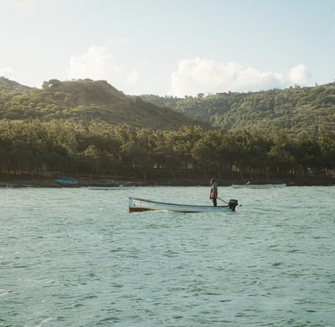 Fisherman in Rodrigues standing on his moving boat with the beautiful backdrop of the hills