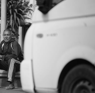 A man sits on a step, resting and observing the street in Rodrigues