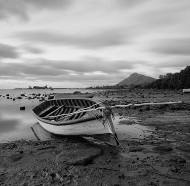 Long exposure shot of a wooden boat on a rocky shoreline at Petite Case Noyale in Mauritius 