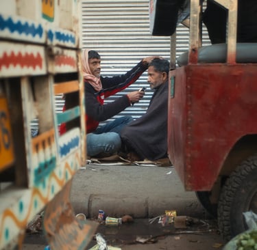 Street barber giving a haircut on a pavement in Old Delhi