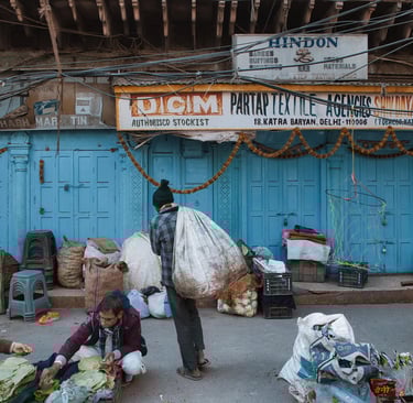 Workers sorting goods and carrying sacks outside closed shops in Old Delhi.