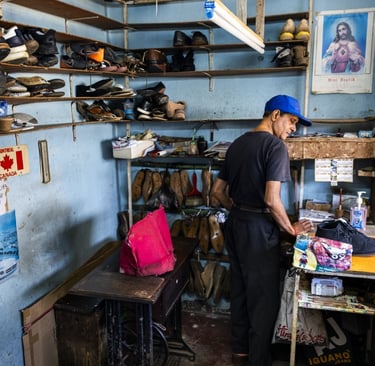 Mauritian cobbler in a small workshop surrounded by shoes, Cape Town Photography Festival 2025