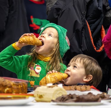 a boy and girl eating pastries at a table