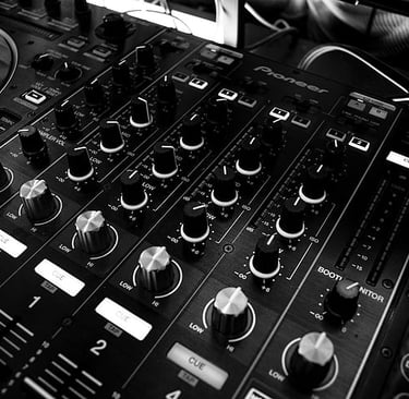 A close-up view of a professional DJ mixer with multiple knobs, faders, and controls.