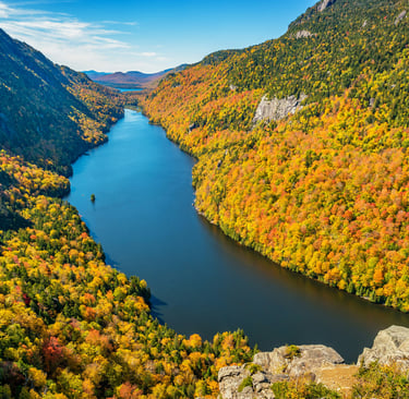 a river flowing through a valley with a mountain in the background