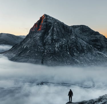 a person standing on a mountain top with a mountain in the background