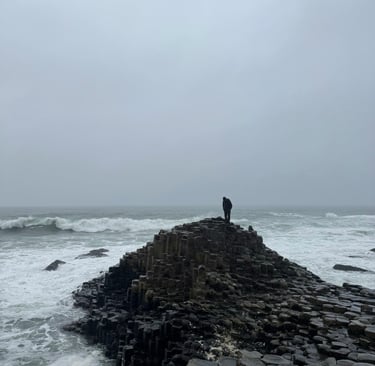 a person standing on a rock formation in the ocean