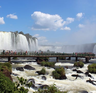 a bridge over a waterfall in the middle of a river