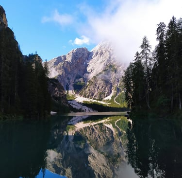 a mountain scene with a lake and a bridge