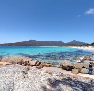 Freycinet bay sandy beach with rocks and mountain view