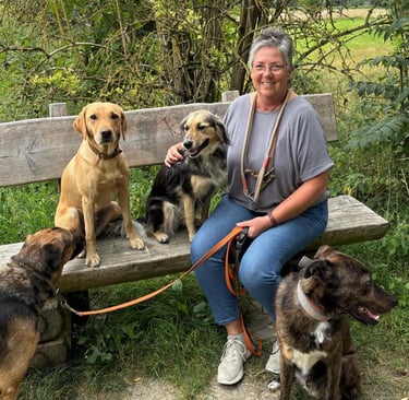 Marion Lindhof sitzt mit ihren Hunden im Park auf einer Bank.