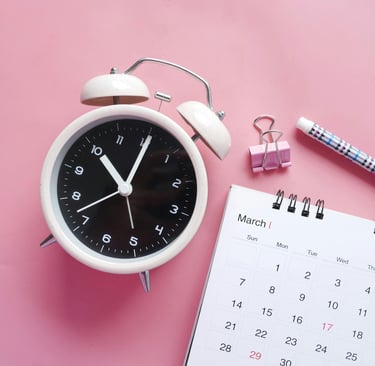 White alarm clock with pen and March calendar on a pink background