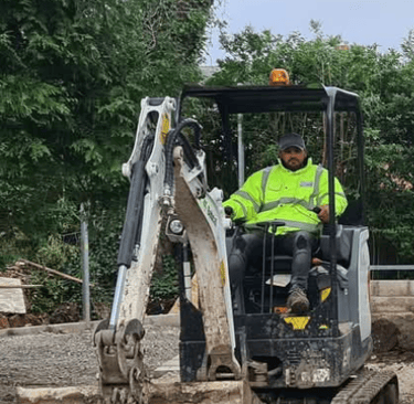 Mini digger with driver at work in Winchmore hill London