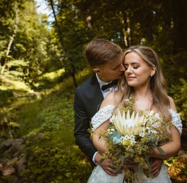 a bride and groom standing in a forest