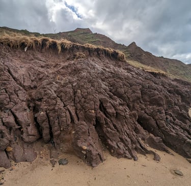 close up of a raw, cracked brown or terracotta clay pile at the edge of a cliff