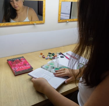 uma mulher está sentada a mesa lendo um livro sobre cristais
