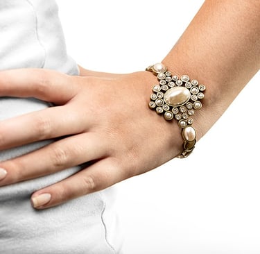 a mão de uma mulher usando uma pulseira com pérolas