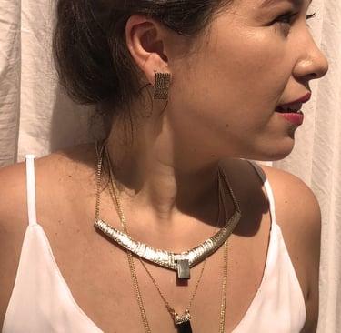 uma mulher veste uma blusa branca com um mix de colares com cristas e obsidiana negra