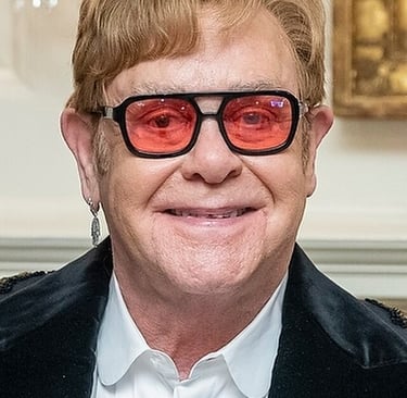 Sir Elthon John in posa con occhiali con lenti rosse