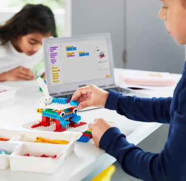 Elementary students build a robot with colorful blocks and program it on a tablet.