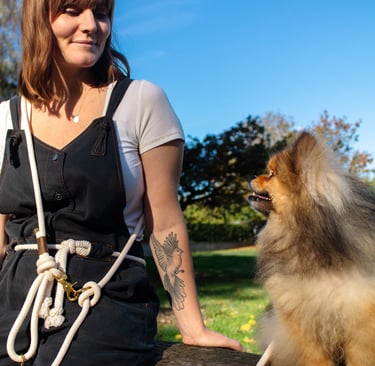 a woman in overalls and overalls sitting on a bench with a dog