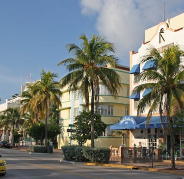Pastel-colored Art Deco hotel facade in Miami Beach's historic district with palm trees"