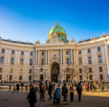 Tourists walk in front of the Hofburg Palace at Michaelerplatz in Vienna, Austria.