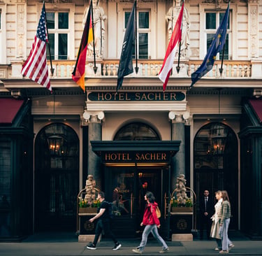 The grand entrance of Hotel Sacher in Vienna featuring historic architecture and international flags.
