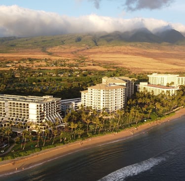 Aerial view of luxury Kaanapali beach resorts and hotels on the Maui coastline at sunset.