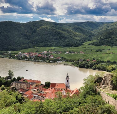 Panoramic view of Durnstein village, Danube River, and Wachau Valley vineyards in Austria.