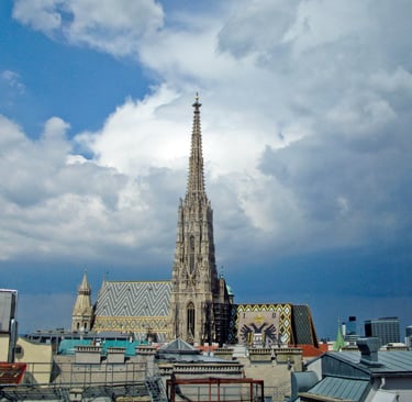 St. Stephen's Cathedral in Vienna featuring its Gothic spire and patterned tile roof under a cloudy sky.