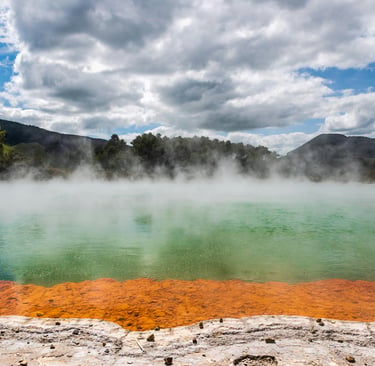 Steam rises from the colorful Champagne Pool at Wai-O-Tapu Thermal Wonderland in New Zealand.