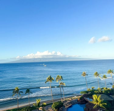 Panoramic ocean view of a tropical Maui beach resort with palm trees and blue Pacific waters.