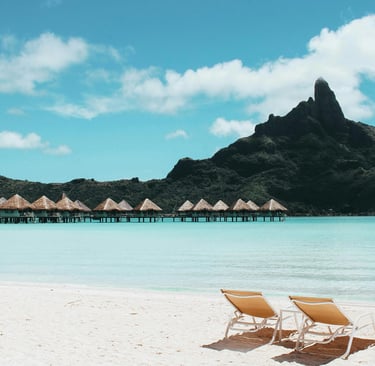 Luxury overwater bungalows in Bora Bora with a sandy beach and Mount Otemanu view.