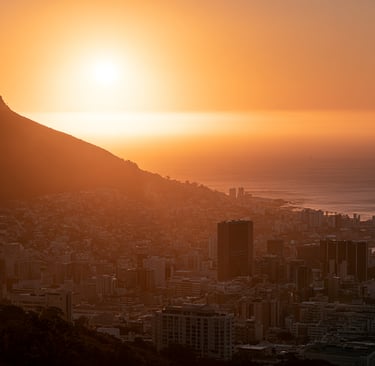 Golden sunset over Cape Town city skyline with Lion's Head mountain and Atlantic Ocean.