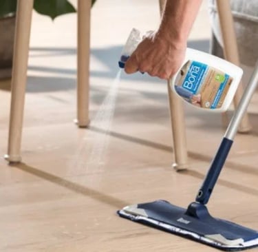 a person cleaning a wooden floor with a mop
