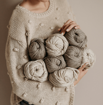 Pelotes de laine dans les bras d'une femme qui fait du crochet