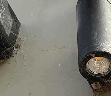 Accumulated spider webs on a security camera and downlighting on a commercial premises
