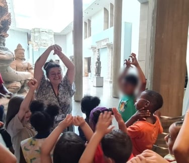 Des enfants tendent les bras vers le haut au musée Guimet