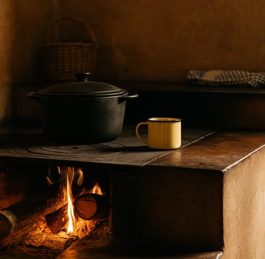 Fogão a lenha aceso em cozinha rústica, com panela de ferro, chaleira fumegando e utensílios antigos