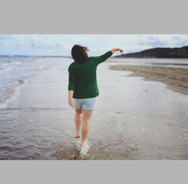 mulher andando feliz na praia
