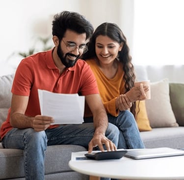 A couple reviewing their budget on a laptop or writing in a budget planner for wedding