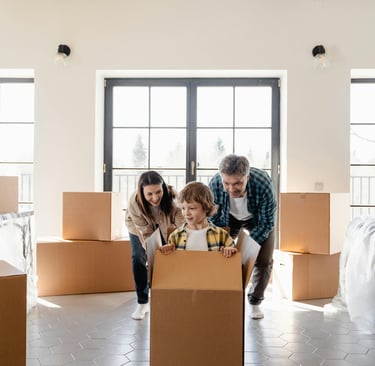 A family moving into a home with a child playing in a moving box.