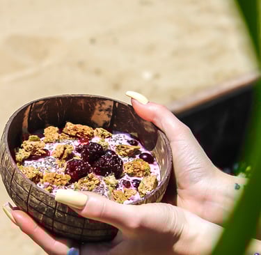 a person holding a coconut bowl of with greek yoghurt, granola and fruit
