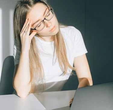 a woman in glasses and a white shirt is sitting at a table with a laptop