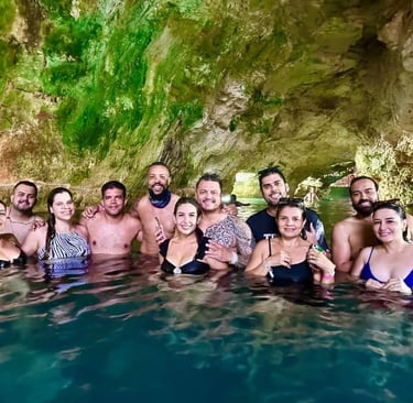 Grupo de turistas nadando em um cenote paradisíaco em Punta Cana, cercado por formações rochosas 